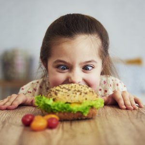 Playful girl looking at delicious hamburger