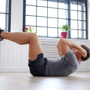 Athletic middle age man doing stomach workouts at home.