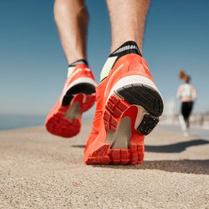 Close up runner feet. Man runner legs and shoes in action on road outdoors at road near sea. Male athlete model.