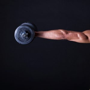 Strong and muscular guy with dumbbell over black background